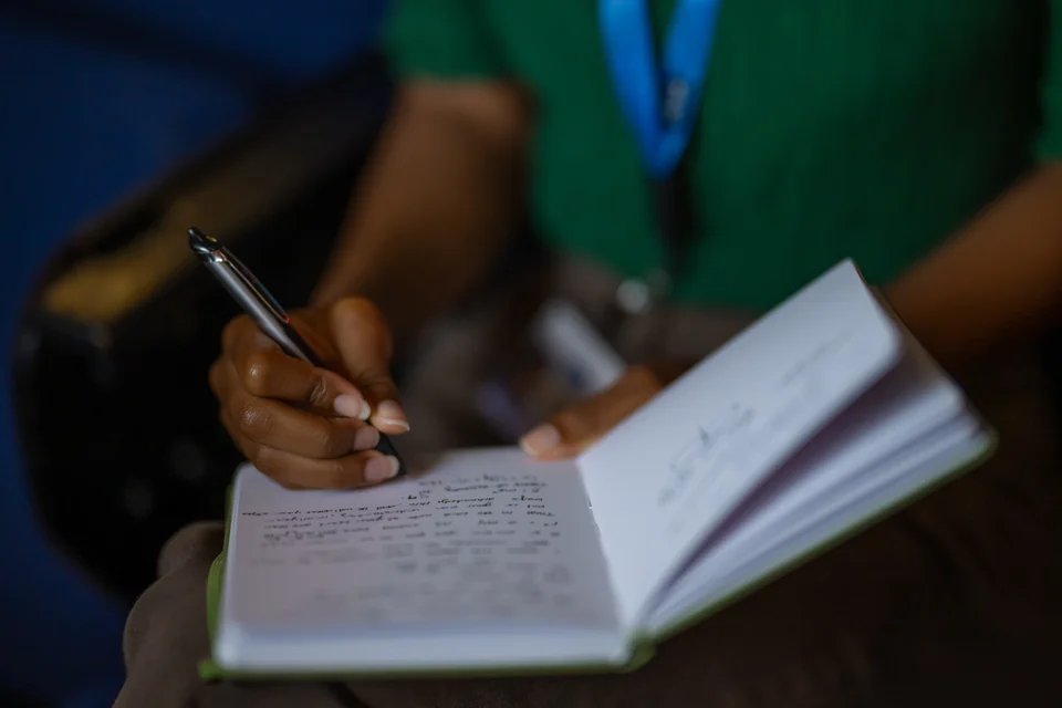 female student sitting in auditorium writing in their notebook
